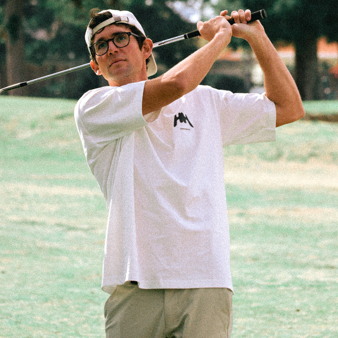 Man holding golf club in white tee