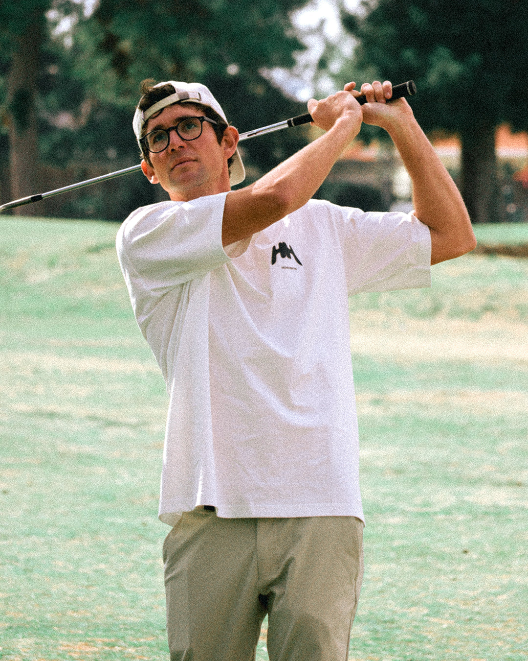 Man holding golf club in white tee