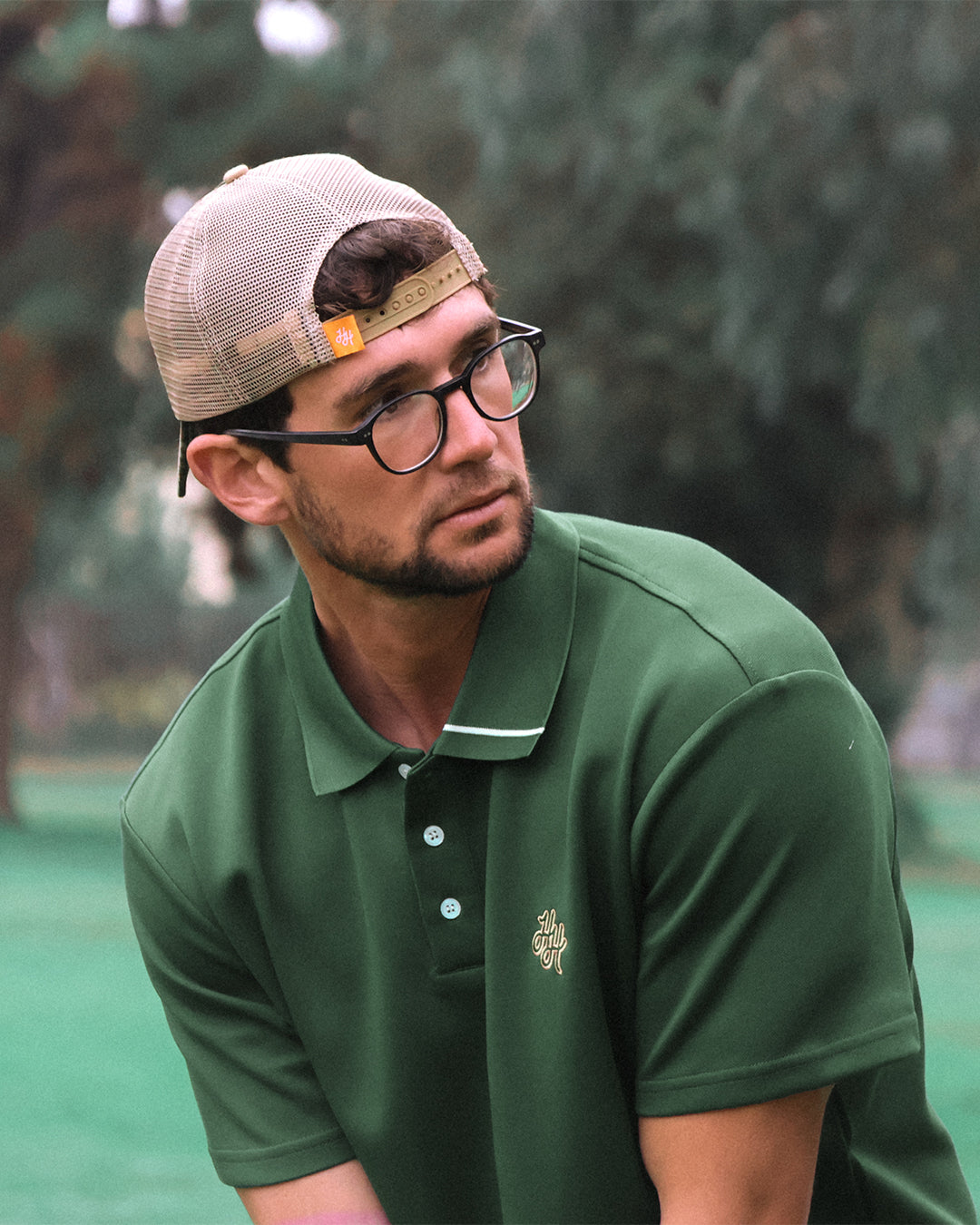 Man wearing a green polo shirt and beige cap outdoors