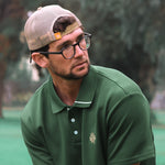 Man wearing a green polo shirt and beige cap outdoors