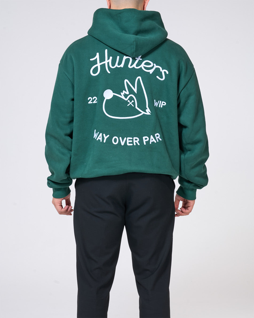 Green hoodie with white text and graphics on the back, worn by a person against a white background