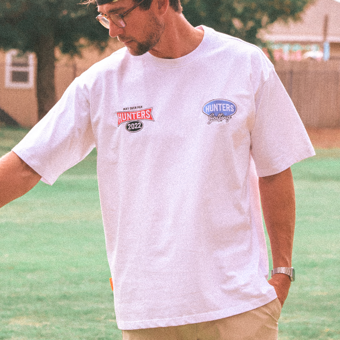 Man wearing a white t-shirt with logos outdoors