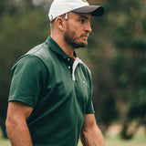 Man wearing a green polo shirt and white cap on a golf course