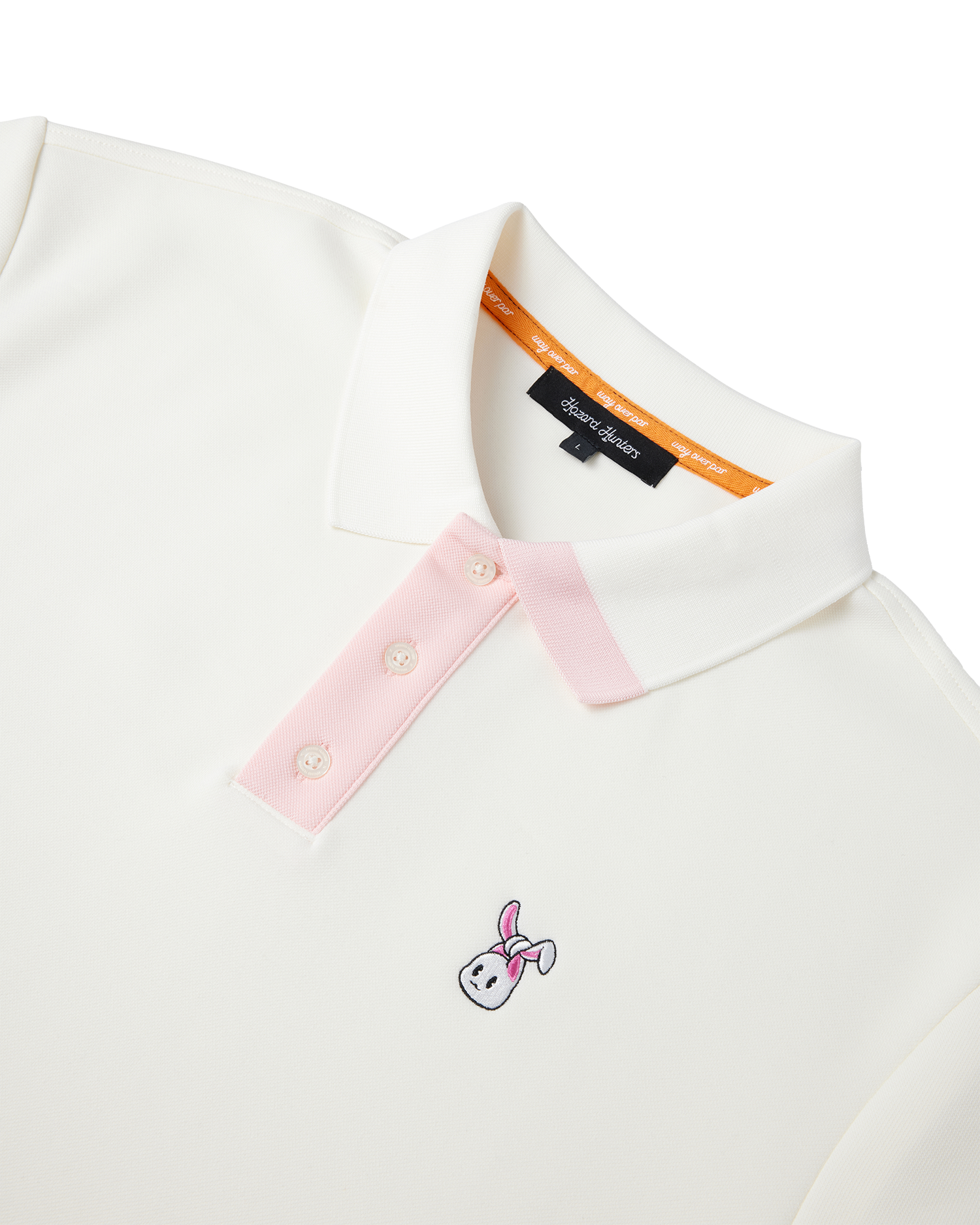A cream polo shirt with a white and pink embroidered bunkie emblem on the chest, pink contrast on the button placket and collar, and a relaxed fit.