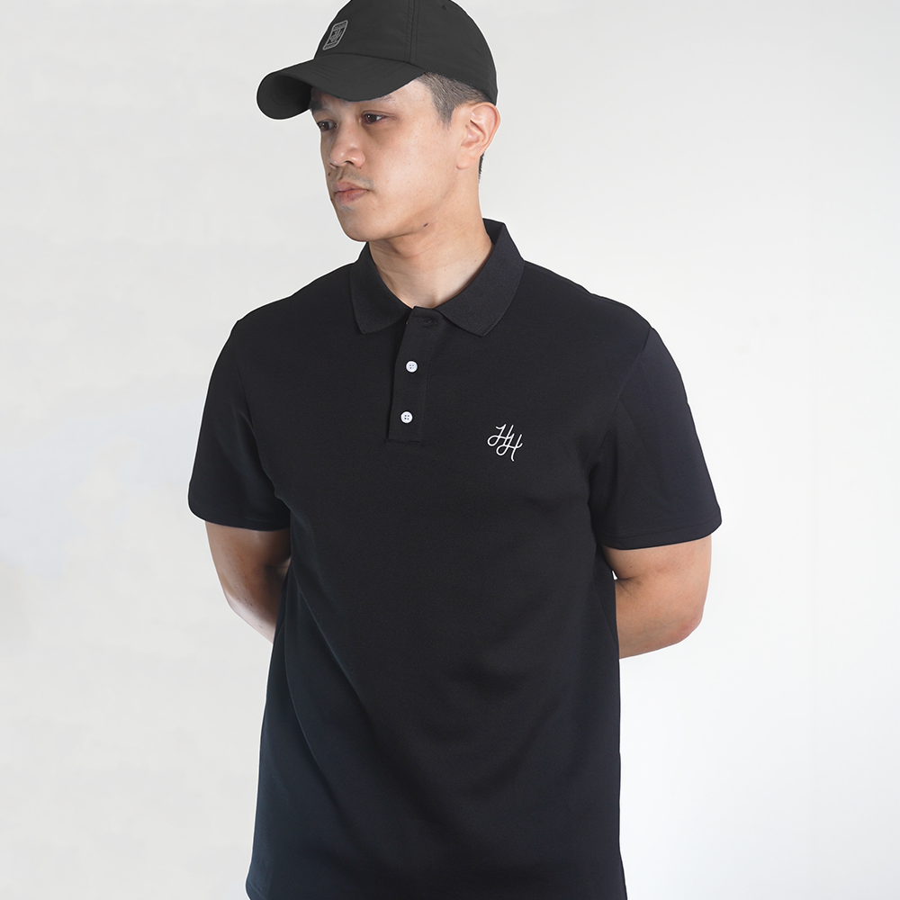Man wearing black polo shirt in white studio setting
