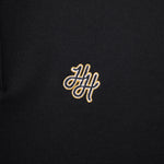 Black polo shirt with gold embroidered logo on a black background
