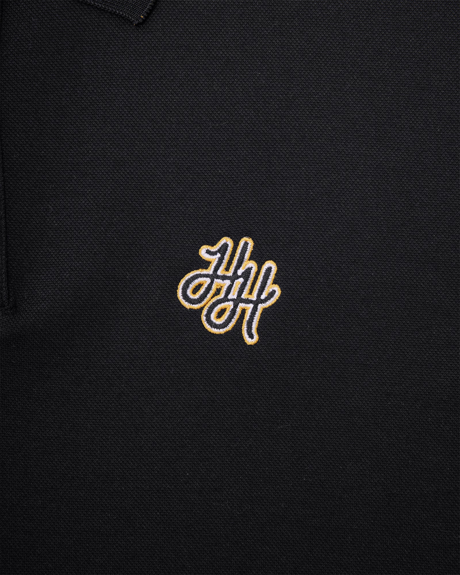 Black polo shirt with gold embroidered logo on a black background