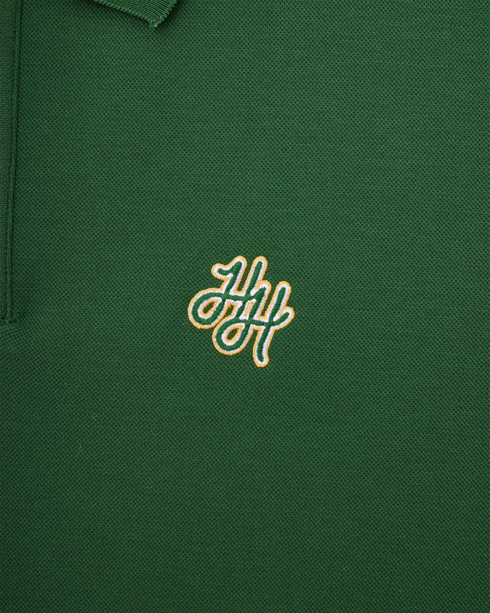 Green polo shirt with a gold embroidered logo on a close-up view