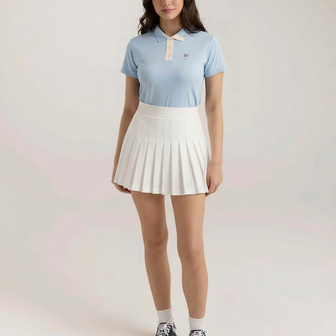 Woman wearing a light blue polo shirt and white pleated skirt on a plain background